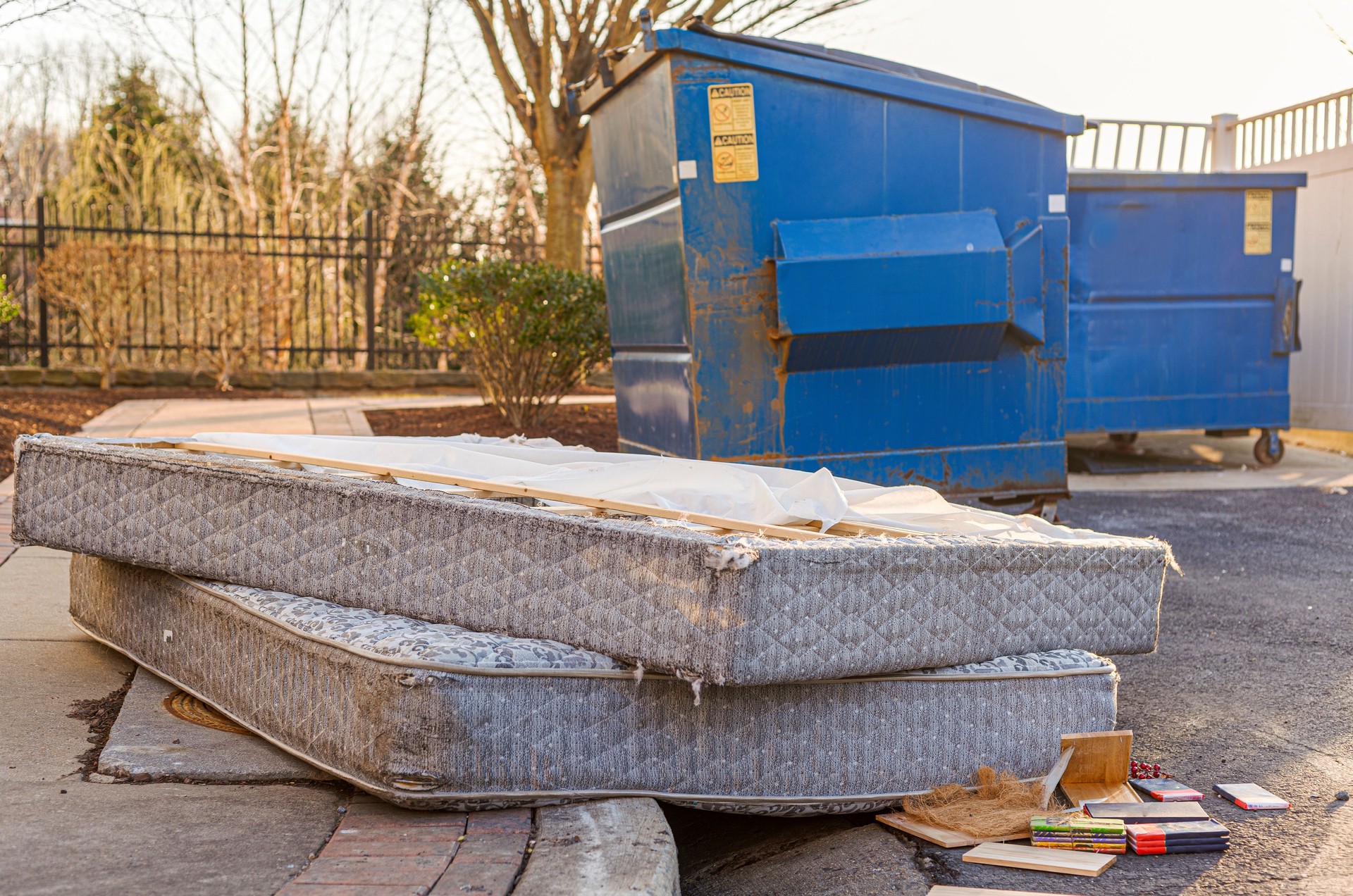 old mattresses dumped by a dumpster creating eyesore